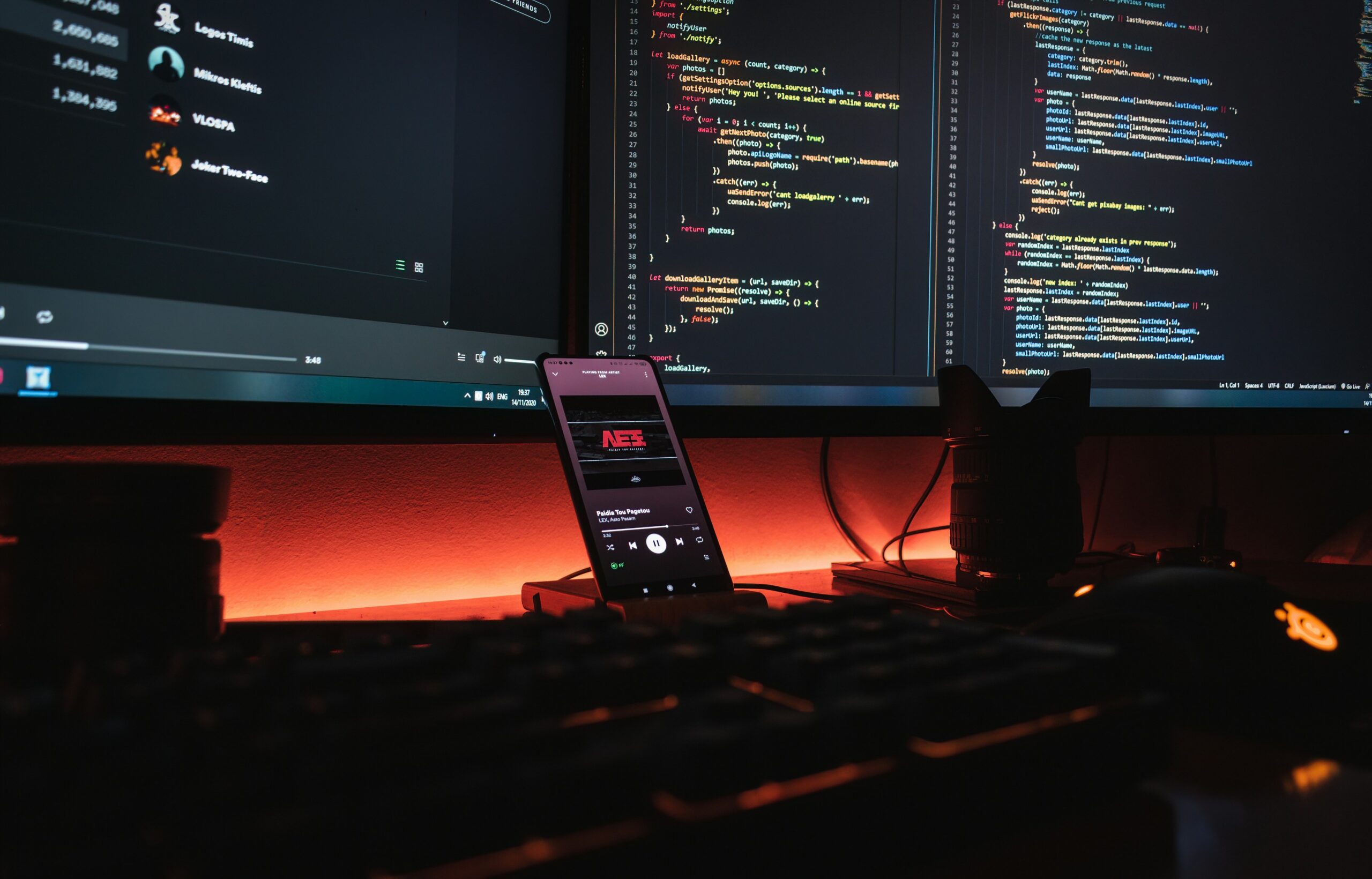 A WordPress developer's workstation with dual monitors displaying code, lit by warm orange ambient lighting