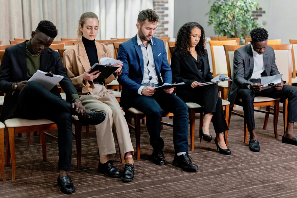 Professionals sitting in a row reviewing resumes during a hiring process, illustrating how global staffing agencies source and evaluate international talent.