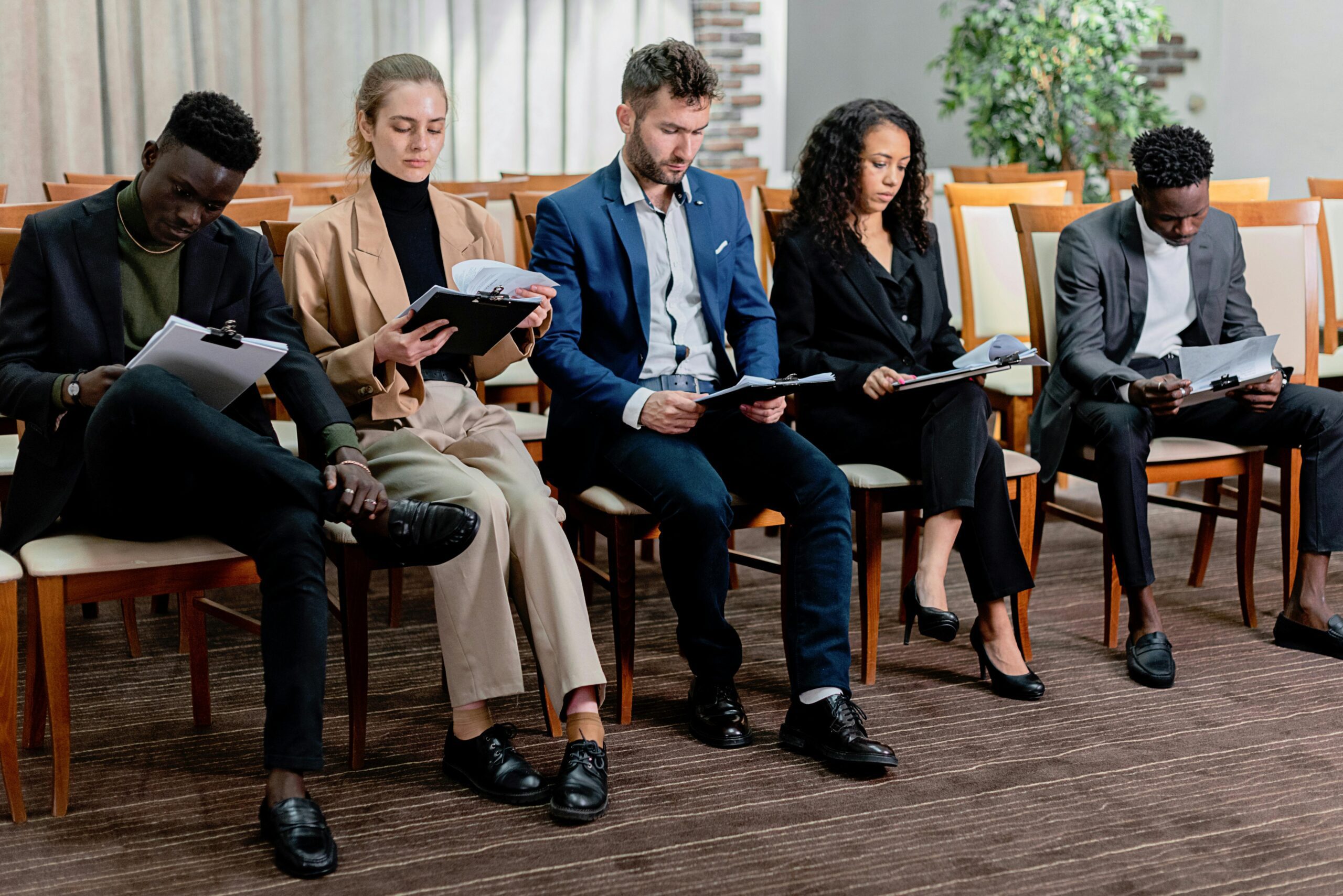 Professionals sitting in a row reviewing resumes during a hiring process, illustrating how global staffing agencies source and evaluate international talent.