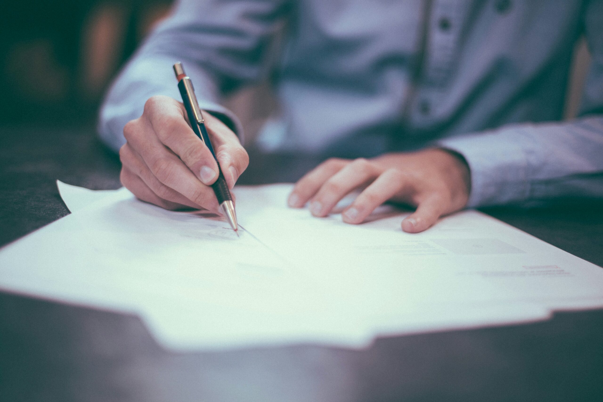 Hand signing contract on desk, compliance recruitment agencies paperwork, business agreement and hiring process close-up